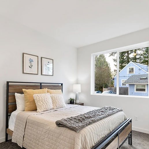 Bedroom with queen bed, wood headboard and garden-view window