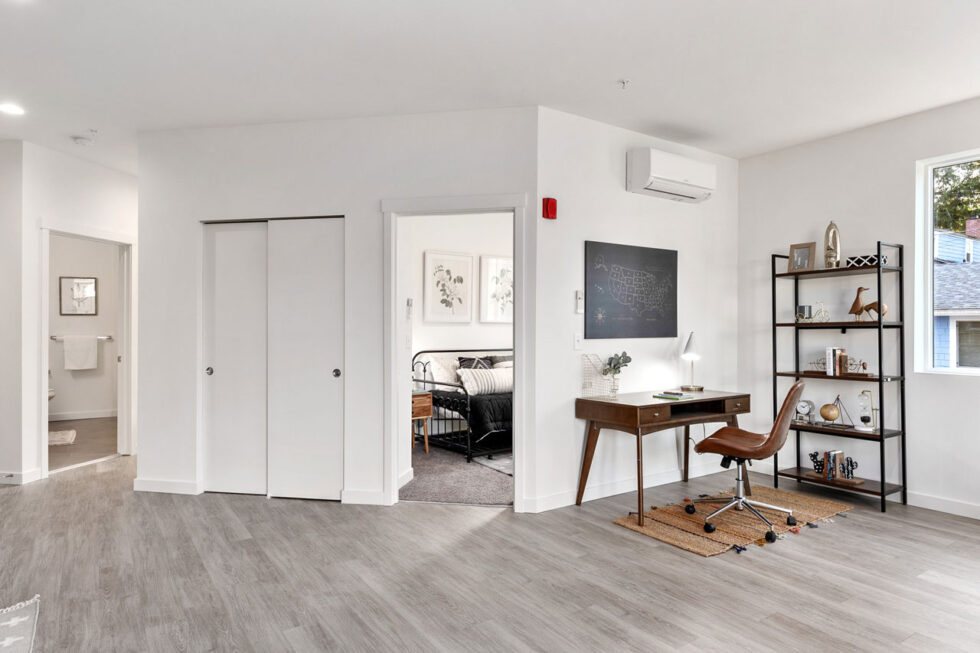 Open living area with work desk and a view into the bedroom